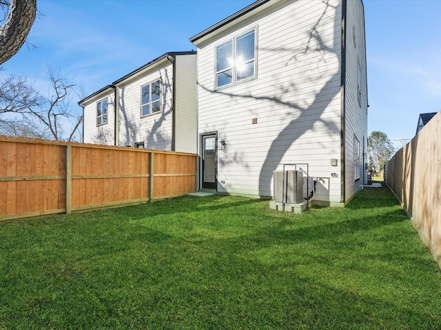 back of property featuring central air condition unit and a lawn