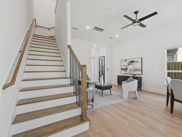 stairs with hardwood / wood-style floors and ceiling fan