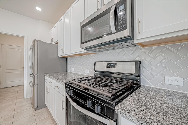 kitchen with light tile patterned floors, light stone countertops, white cabinetry, and appliances with stainless steel finishes