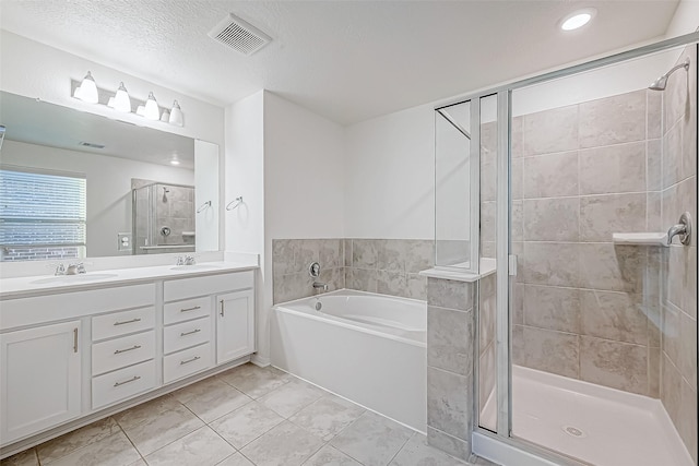 bathroom featuring plus walk in shower, vanity, a textured ceiling, and tile patterned flooring