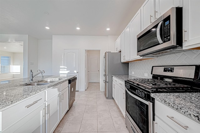 kitchen with light stone countertops, white cabinetry, light tile patterned floors, and stainless steel appliances