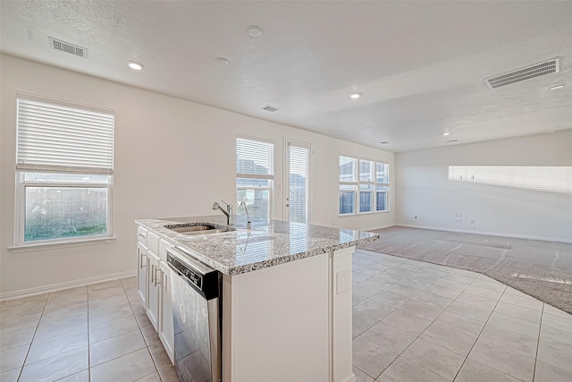 kitchen featuring white cabinetry, dishwasher, sink, light stone counters, and a kitchen island with sink