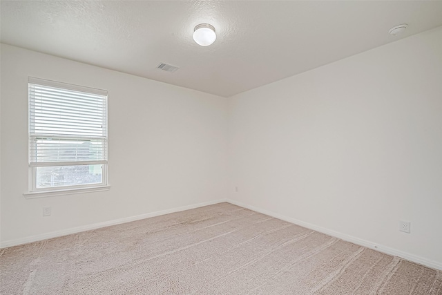 carpeted empty room with a textured ceiling