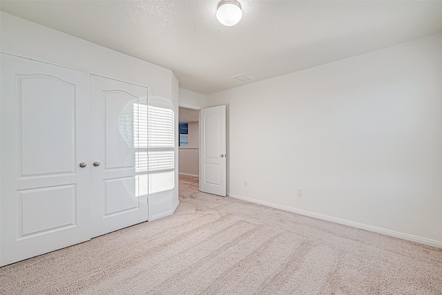 unfurnished bedroom featuring a closet, light colored carpet, and a textured ceiling