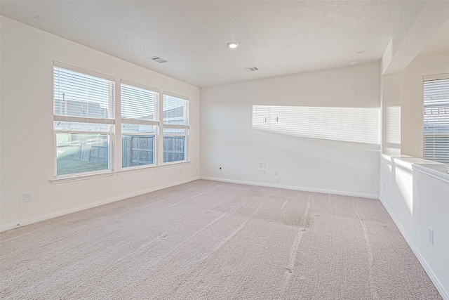 empty room with light colored carpet and a textured ceiling