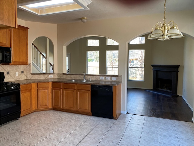 kitchen with black appliances, sink, decorative backsplash, light tile patterned floors, and a chandelier