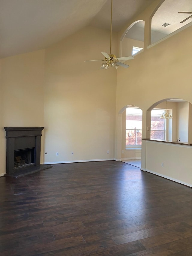 unfurnished living room featuring high vaulted ceiling, dark wood-type flooring, and ceiling fan with notable chandelier