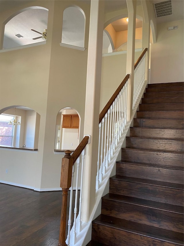 stairs with hardwood / wood-style floors and ceiling fan with notable chandelier