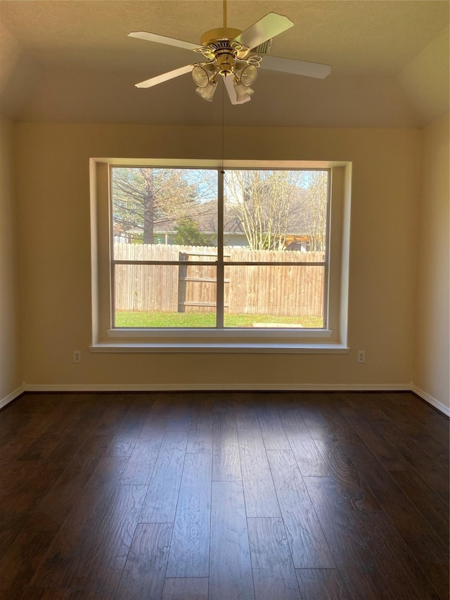 spare room featuring dark hardwood / wood-style floors, vaulted ceiling, and ceiling fan