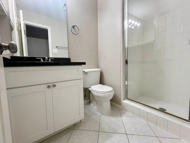 bathroom featuring tile patterned flooring, a shower with door, vanity, and toilet