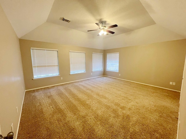 empty room with carpet flooring, vaulted ceiling, a raised ceiling, and ceiling fan