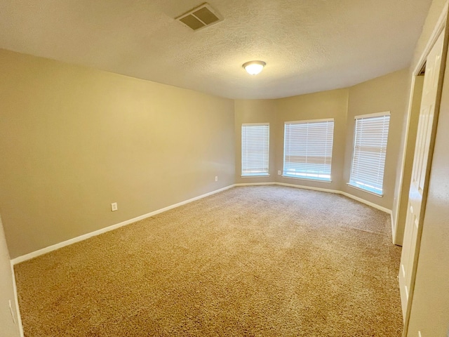 carpeted empty room featuring a textured ceiling