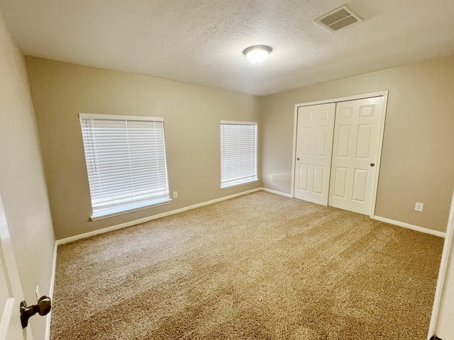 unfurnished bedroom with a textured ceiling, carpet floors, and a closet