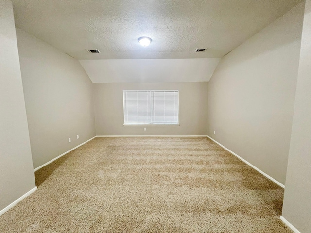 carpeted empty room featuring a textured ceiling and vaulted ceiling