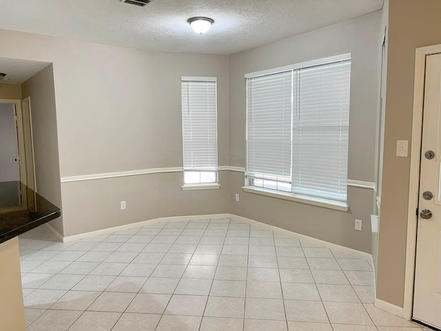 tiled empty room featuring a textured ceiling