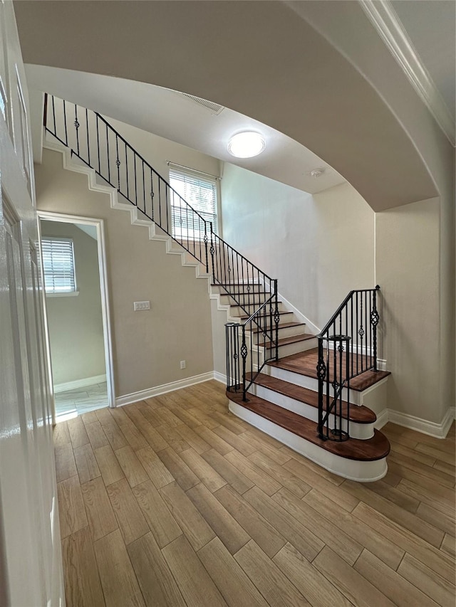 staircase featuring wood-type flooring and ornamental molding