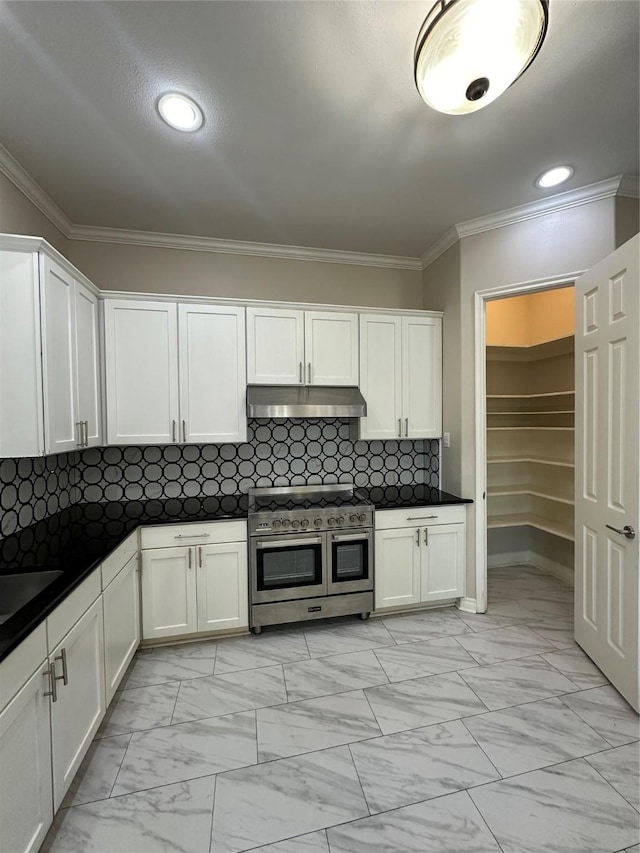 kitchen with tasteful backsplash, range with two ovens, white cabinetry, and crown molding