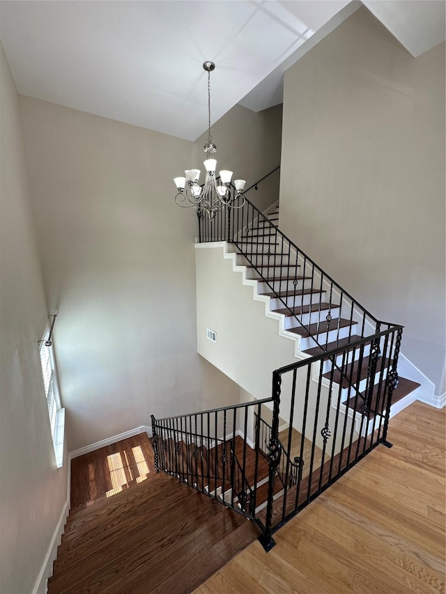 staircase featuring wood-type flooring and an inviting chandelier