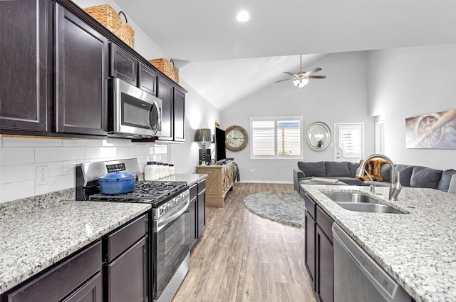 kitchen featuring lofted ceiling, sink, appliances with stainless steel finishes, tasteful backsplash, and dark brown cabinetry