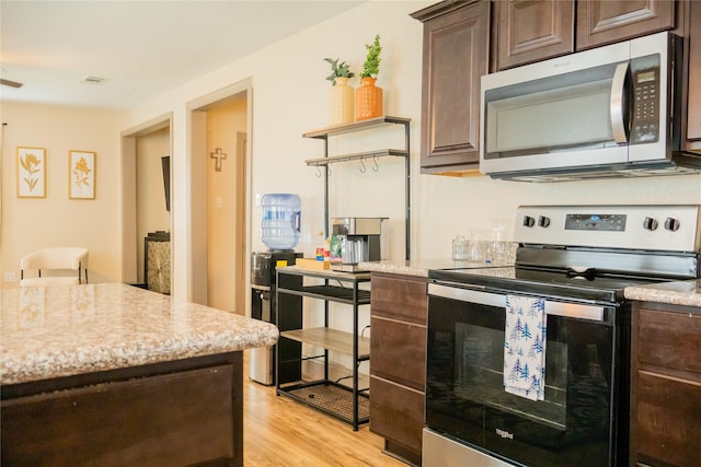 kitchen featuring light stone countertops, dark brown cabinetry, appliances with stainless steel finishes, and light hardwood / wood-style flooring