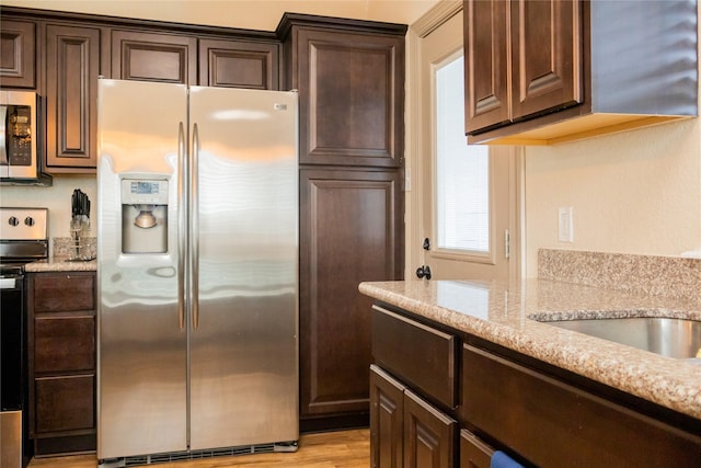 kitchen with dark brown cabinetry, stainless steel fridge with ice dispenser, and range