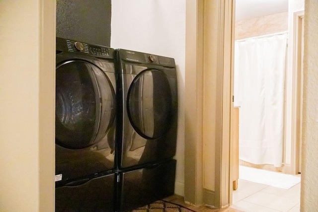 clothes washing area featuring light tile patterned flooring and washing machine and clothes dryer