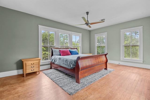 bedroom featuring hardwood / wood-style floors, ceiling fan, and multiple windows