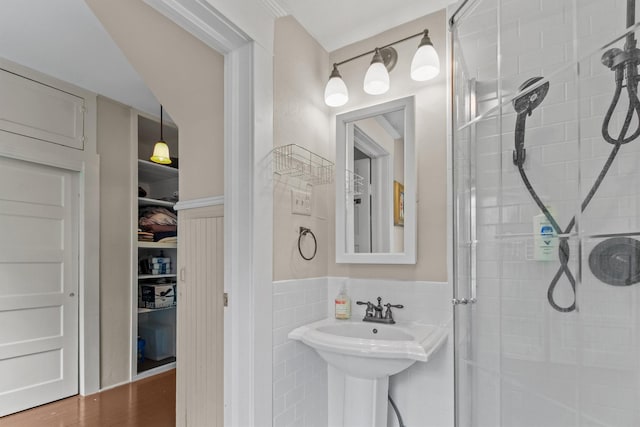 bathroom with hardwood / wood-style flooring, an enclosed shower, and tile walls