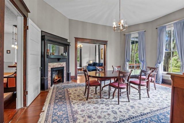 dining room featuring a stone fireplace, a chandelier, and wood-type flooring