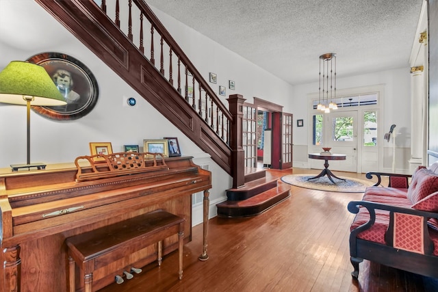 entryway featuring hardwood / wood-style floors, an inviting chandelier, a textured ceiling, and french doors