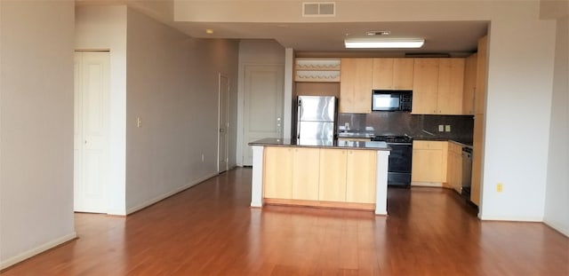 kitchen featuring black appliances, a center island, backsplash, and light brown cabinetry