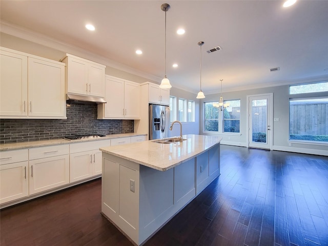 kitchen with pendant lighting, a center island with sink, sink, appliances with stainless steel finishes, and white cabinetry