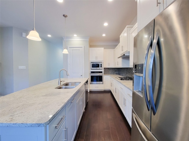 kitchen featuring appliances with stainless steel finishes, sink, a center island with sink, decorative light fixtures, and white cabinetry