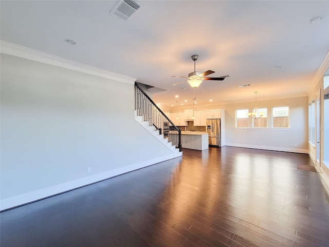 unfurnished living room with ceiling fan with notable chandelier, dark hardwood / wood-style flooring, and ornamental molding