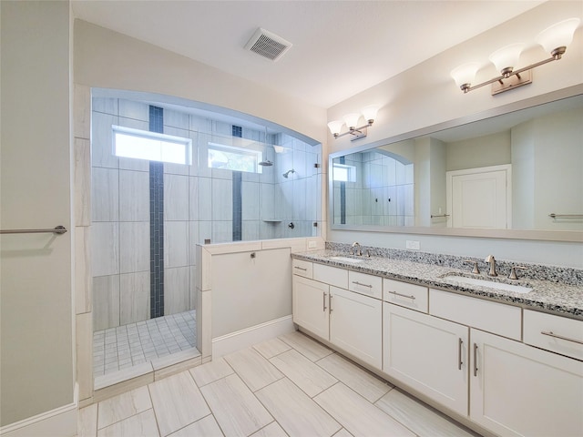 bathroom with tile patterned flooring, vanity, and tiled shower