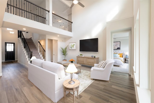 living room featuring hardwood / wood-style floors, ceiling fan, and a towering ceiling