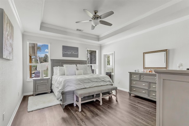 bedroom featuring a tray ceiling, dark hardwood / wood-style flooring, ceiling fan, and crown molding