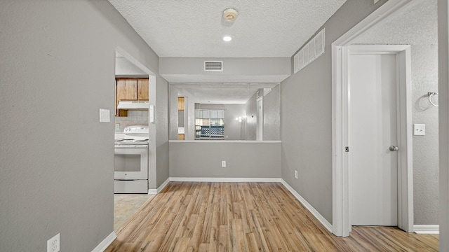 kitchen with range, backsplash, a textured ceiling, and light hardwood / wood-style flooring