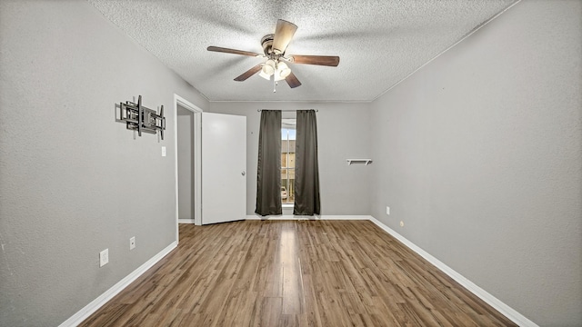 unfurnished room with hardwood / wood-style flooring, ceiling fan, and a textured ceiling