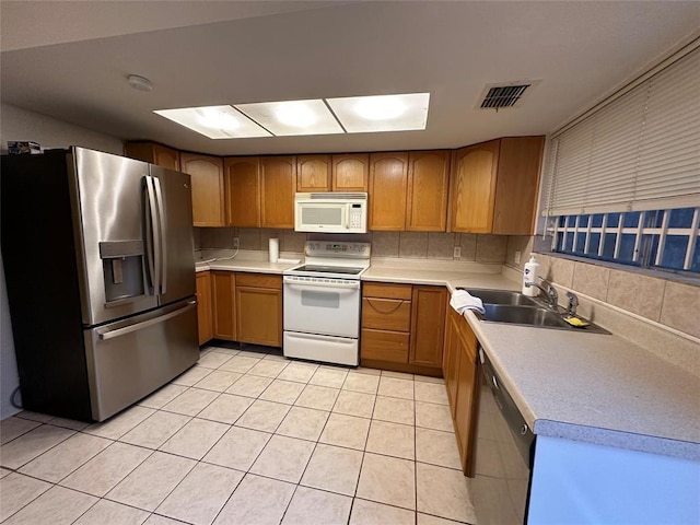 kitchen with backsplash, light tile patterned flooring, sink, and appliances with stainless steel finishes