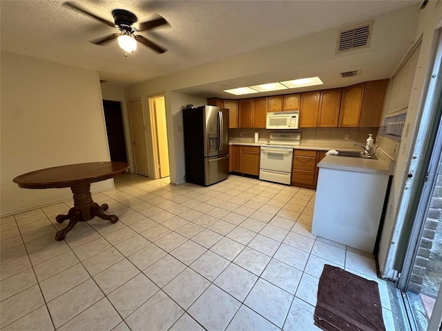 kitchen featuring ceiling fan, stainless steel fridge, light tile patterned floors, a textured ceiling, and range