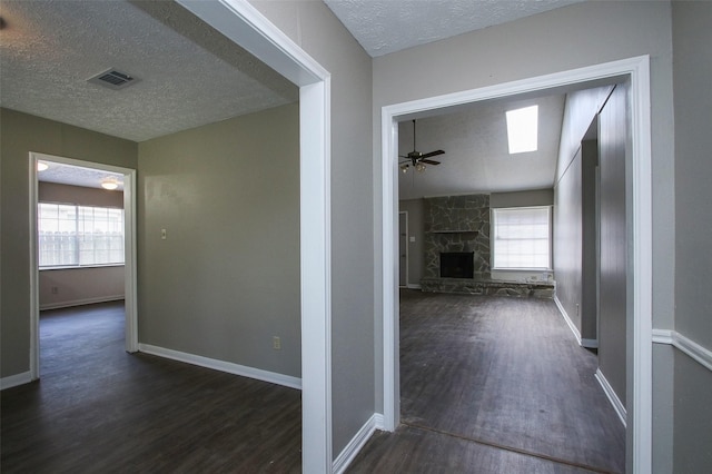 corridor with lofted ceiling, dark hardwood / wood-style flooring, and a textured ceiling