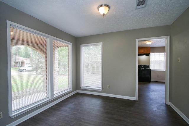 empty room with dark hardwood / wood-style flooring and a textured ceiling