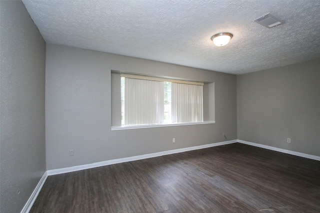 spare room with dark hardwood / wood-style flooring and a textured ceiling