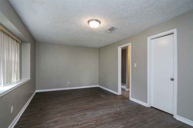 unfurnished room with dark wood-type flooring and a textured ceiling