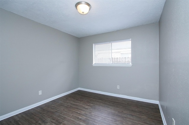 spare room with dark hardwood / wood-style floors and a textured ceiling