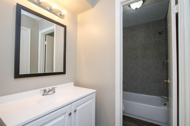 full bathroom featuring hardwood / wood-style floors, vanity, tiled shower / bath combo, and toilet