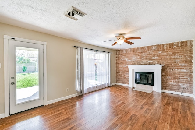 unfurnished living room with ceiling fan, plenty of natural light, a textured ceiling, and hardwood / wood-style flooring