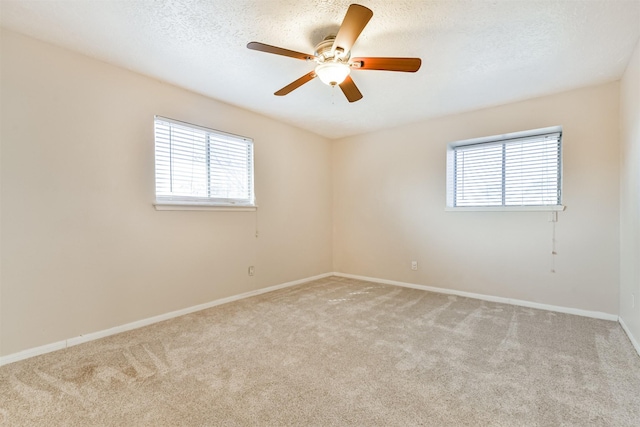 carpeted spare room featuring a textured ceiling, ceiling fan, and a healthy amount of sunlight