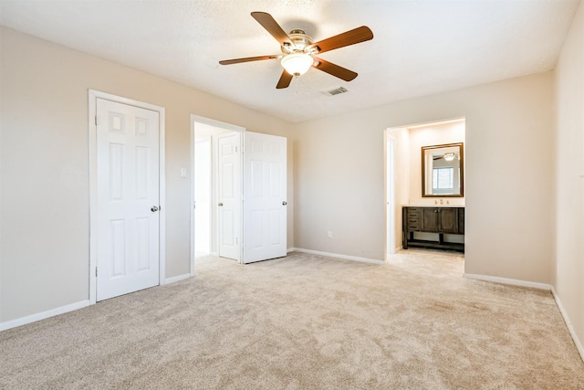 unfurnished bedroom with ensuite bathroom, ceiling fan, and light colored carpet